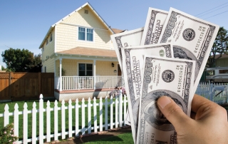 Casa con una mano al frente con dinero
