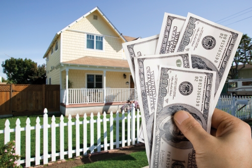 Casa con una mano al frente con dinero